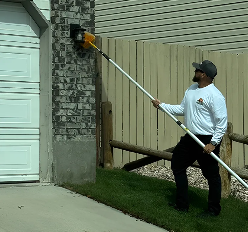 Salt Lake City pest control technician treating garage eaves with an extension pole